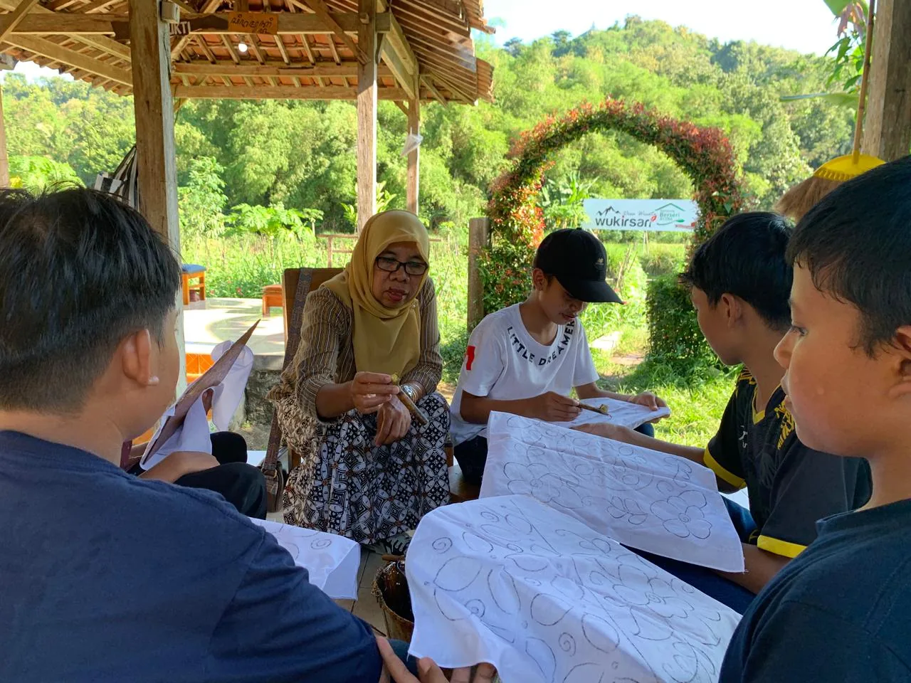 Perajin batik Giriloyo membimbing anak-anak mencanting di pendopo Wukirsari, Imogiri, Bantul